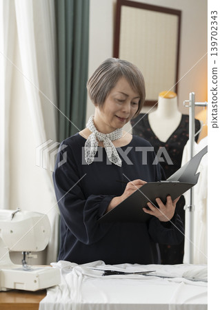 資深女設計師在她們的工作室裡製作服裝。 資深女設計師在她們的工作室裡製作服裝。 139702343