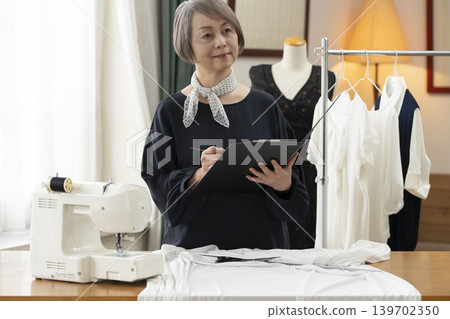 資深女設計師在她們的工作室裡製作服裝。 資深女設計師在她們的工作室裡製作服裝。 139702350