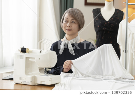 資深女設計師在她們的工作室裡製作服裝。 資深女設計師在她們的工作室裡製作服裝。 139702356