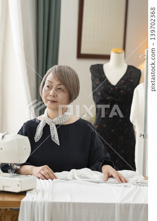 資深女設計師在她們的工作室裡製作服裝。 資深女設計師在她們的工作室裡製作服裝。 139702368