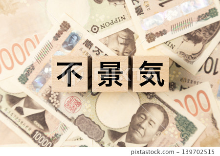 一塊寫著「經濟衰退」字樣的磚塊,以及許多面額為10,000日圓的鈔票。 一塊寫著「經濟衰退」字樣的磚塊,以及許多面額為10,000日圓的鈔票。 139702515