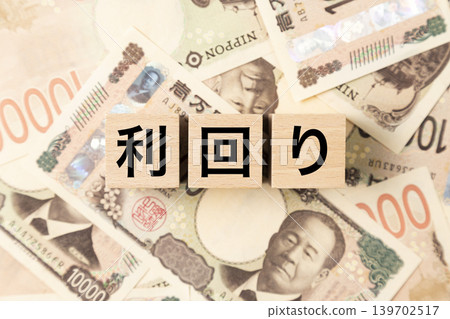 A block with the word "yield" written on it and lots of 10,000 yen bills. A block with the word "yield" written on it and lots of 10,000 yen bills. 139702517