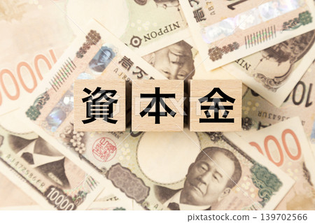 一塊標示「資本」的鈔票和大量10,000日元紙幣。 一塊標示「資本」的鈔票和大量10,000日元紙幣。 139702566