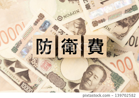 一塊標示「國防開支」的鈔票和大量10,000日圓面額的鈔票。 一塊標示「國防開支」的鈔票和大量10,000日圓面額的鈔票。 139702582