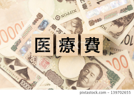 A block labeled "Medical Expenses" and many 10,000 yen bills A block labeled "Medical Expenses" and many 10,000 yen bills 139702655