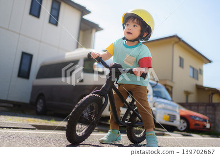 A 2-year-old boy riding a balance bike. A 2-year-old boy riding a balance bike. 139702667
