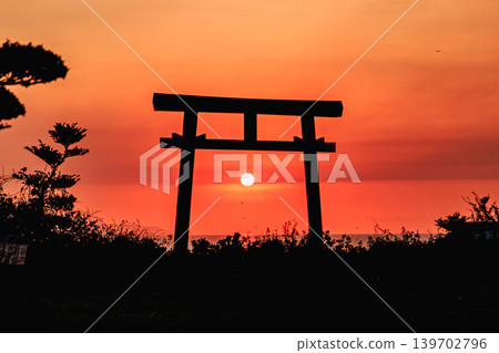 The silhouette of the torii gate of Yahazudake Shrine floating in the crimson sky. The silhouette of the torii gate of Yahazudake Shrine floating in the crimson sky. 139702796