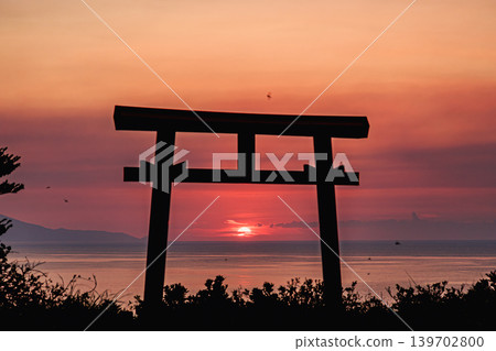 The torii gate of Yahazudake Shrine and the seascape of Yakushima Island, illuminated against the evening sky. The torii gate of Yahazudake Shrine and the seascape of Yakushima Island, illuminated against the evening sky. 139702800