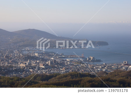 In early May, in Hokkaido, a view of Otaru, Hokkaido, from the observation point on Mount Kenashi, overlooking the harbor and Ishikari Bay, against a blue sky and evening twilight. 139703178