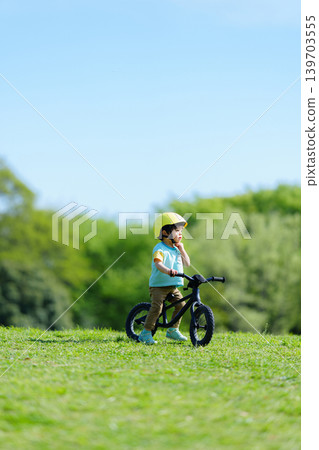 A 2-year-old boy riding a balance bike in the park. A 2-year-old boy riding a balance bike in the park. 139703555