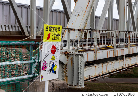 Safety sign on railway bridge: "Caution: High-voltage power lines" and the truss structure of the railway bridge. Safety sign on railway bridge: "Caution: High-voltage power lines" and the truss structure of the railway bridge. 139703996