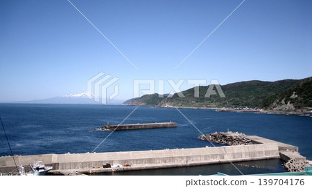 A clear blue sky, the blue Sea of Japan, Mount Chokai with its remaining snow, and a fishing port. A clear blue sky, the blue Sea of Japan, Mount Chokai with its remaining snow, and a fishing port. 139704176