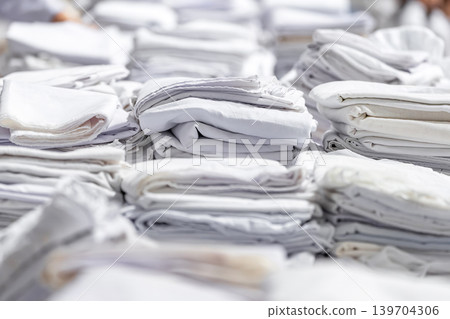 Stacks of folded white fabric on a smooth table organized piles clean textile storage preparation material handling. Stacks of folded white fabric on a smooth table organized piles clean textile storage preparation material handling. 139704306