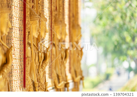 Close view ornate temple door golden thepphanom figure high relief layered carving sacred Thai ornament craftsmanship. Close view ornate temple door golden thepphanom figure high relief layered carving sacred Thai ornament craftsmanship. 139704321