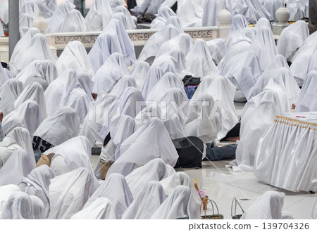 Hundreds of people sitting together covered with white fabric during a traditional spiritual ritual. Symbolic mass gathering expressing unity, faith, purity, and ceremonial devotion. Hundreds of people sitting together covered with white fabric during a traditional spiritual ritual. Symbolic mass gathering expressing unity, faith, purity, and ceremonial devotion. 139704326