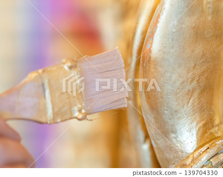 Hands painting gold on deity relief temple wall small brush detail work sacred restoration conservation protection. Hands painting gold on deity relief temple wall small brush detail work sacred restoration conservation protection. 139704330
