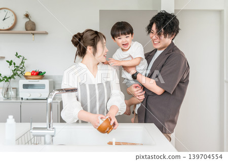 一位家長和孩子在廚房;一位母親和家人在洗碗。 一位家長和孩子在廚房;一位母親和家人在洗碗。 139704554