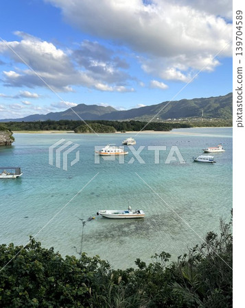 玻璃底船漂浮在石垣島卡比拉灣美麗的水面上。 玻璃底船漂浮在石垣島卡比拉灣美麗的水面上。 139704589