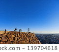 Several people are taking pictures with cameras mounted on tripods from the top of Yonago Castle under a cloudless, sunny sky. 139704618