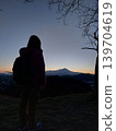The back view of a girl waiting for the sunrise over the mountains in the early morning before dawn. 139704619