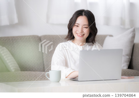 A woman's lifestyle involves using a laptop at home for studying for qualifications and considering investments. A woman's lifestyle involves using a laptop at home for studying for qualifications and considering investments. 139704864