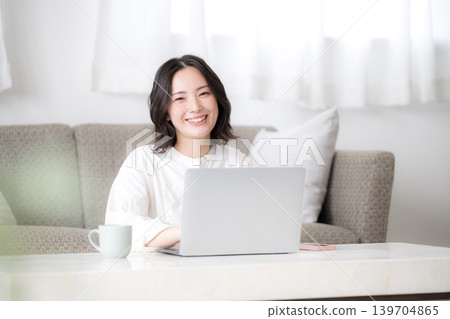 A woman using her laptop at home, studying for qualifications and considering investments – a lifestyle captured from a camera's perspective. A woman using her laptop at home, studying for qualifications and considering investments – a lifestyle captured from a camera's perspective. 139704865