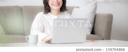 A woman using a laptop at home, studying for qualifications, and thinking about investing – a lifestyle with a camera-facing banner. A woman using a laptop at home, studying for qualifications, and thinking about investing – a lifestyle with a camera-facing banner. 139704866