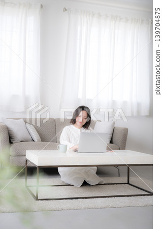 一位女性在家用筆記型電腦學習,準備資格考試,並考慮投資;她面帶微笑,姿態沉思,這是一張廣角全身照。 一位女性在家用筆記型電腦學習,準備資格考試,並考慮投資;她面帶微笑,姿態沉思,這是一張廣角全身照。 139704875