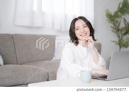 A woman's lifestyle involves using a laptop at home for studying for qualifications and considering investments. A woman's lifestyle involves using a laptop at home for studying for qualifications and considering investments. 139704877