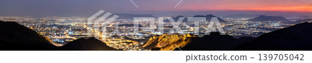 Wide panoramic night view of the illuminated city of Madinah in Saudi Arabia taken from the viewpoint at Jabal Uhud under a twilight sky. 139705042