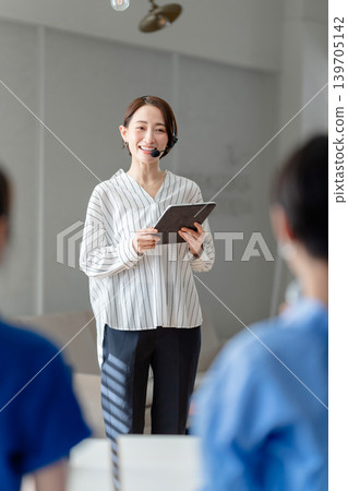 A businesswoman speaking while holding a tablet. A businesswoman speaking while holding a tablet. 139705142