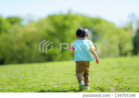 A 2-year-old boy playing on a hill in the park. A 2-year-old boy playing on a hill in the park. 139705166