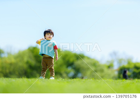 A 2-year-old boy playing on a hill in the park. A 2-year-old boy playing on a hill in the park. 139705176