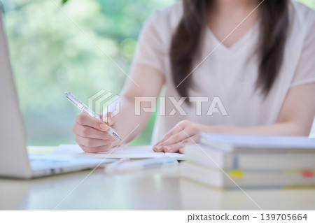 A young woman studying while looking at her computer. A young woman studying while looking at her computer. 139705664