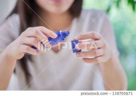 一位二十多歲的女性正在塗抹防曬乳。 一位二十多歲的女性正在塗抹防曬乳。 139705671