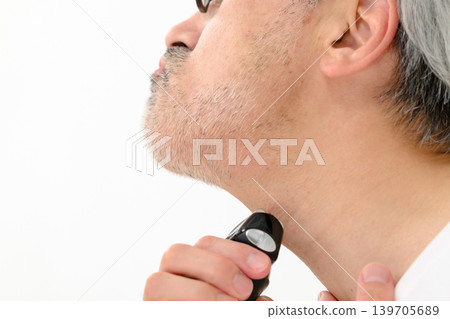 Man shaving his beard with a shaver Man shaving his beard with a shaver 139705689