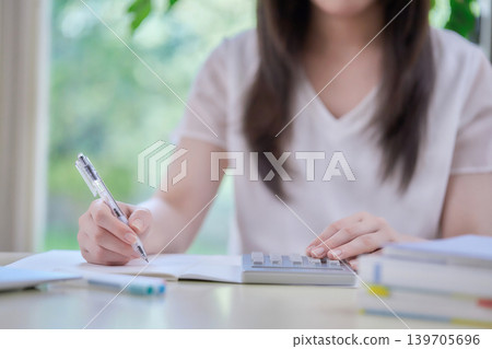 一位年輕女子一邊看著電腦一邊學習。 一位年輕女子一邊看著電腦一邊學習。 139705696