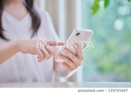Young woman looking at her smartphone in her room Young woman looking at her smartphone in her room 139705697