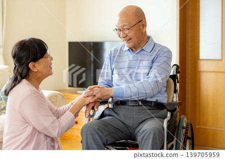 一位坐在輪椅上的老人和一位照顧他的女士。 139705959