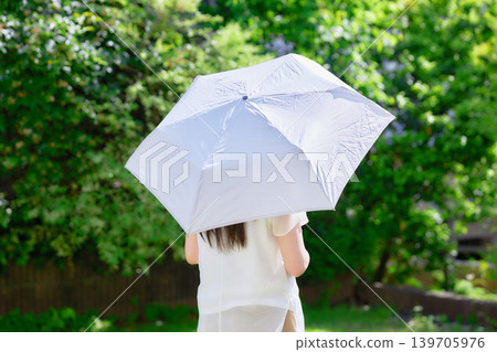 一位二十多歲的女子撐著陽傘。 一位二十多歲的女子撐著陽傘。 139705976