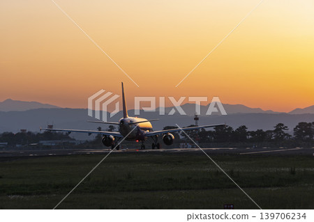 Sendai Airport at dusk: A plane taking off against the setting sun. Natori City, Miyagi Prefecture. Sendai Airport at dusk: A plane taking off against the setting sun. Natori City, Miyagi Prefecture. 139706234