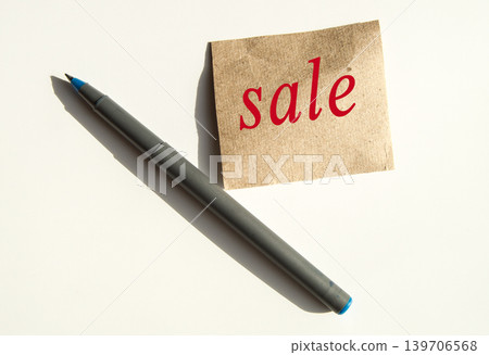The word sale is written on brown wrapping paper, there is a pen next to it The word sale is written on brown wrapping paper, there is a pen next to it 139706568