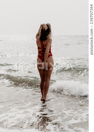 Woman beach swimsuit standing in ocean waves from behind enjoying a peaceful summer seascape during her vacation Woman beach swimsuit standing in ocean waves from behind enjoying a peaceful summer seascape during her vacation 139707164