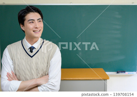 A Japanese male teacher with his arms crossed in front of the blackboard. A Japanese male teacher with his arms crossed in front of the blackboard. 139708154
