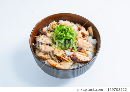 Grilled mackerel rice bowl topped with shredded mackerel and shiso leaves, against a white background. Grilled mackerel rice bowl topped with shredded mackerel and shiso leaves, against a white background. 139708322