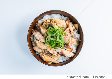 Grilled mackerel rice bowl topped with shredded mackerel and shiso leaves, against a white background. Grilled mackerel rice bowl topped with shredded mackerel and shiso leaves, against a white background. 139708328