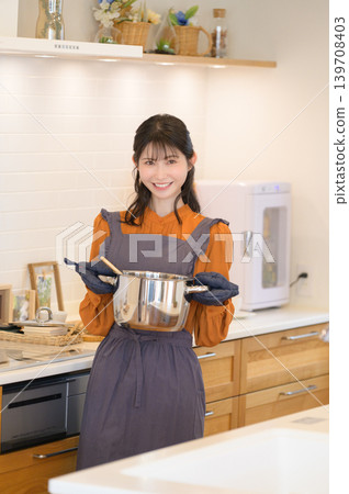 Japanese woman in the kitchen holding a pot Japanese woman in the kitchen holding a pot 139708403