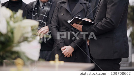 Bible, hands and family at funeral, cemetery or burial ceremony religion by coffin tomb. Holy book, death and grief of people at graveyard, Christian priest reading spiritual gospel and faith in God 139708662