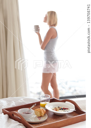 Young woman, view and breakfast in bedroom to relax, morning routine and health with coffee for wellness. Person, cappucino or blonde hair nutrition for fruit detox, calm or healthy food in apartment Young woman, view and breakfast in bedroom to relax, morning routine and health with coffee for wellness. Person, cappucino or blonde hair nutrition for fruit detox, calm or healthy food in apartment 139708741