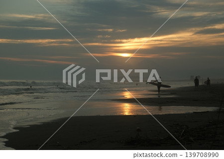 日落時分,人們在久沼海灘衝浪和漫步的剪影。 日落時分,人們在久沼海灘衝浪和漫步的剪影。 139708990
